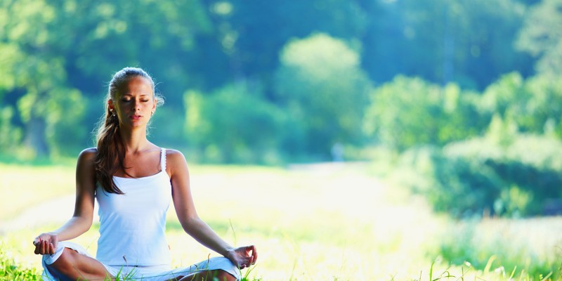 Young woman doing yoga exercise in green park